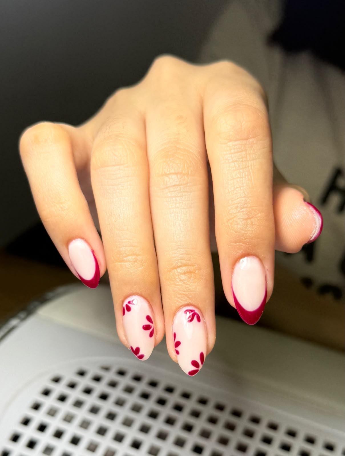 Uñas con base clara, francesitas fucsias y detalles de flores
